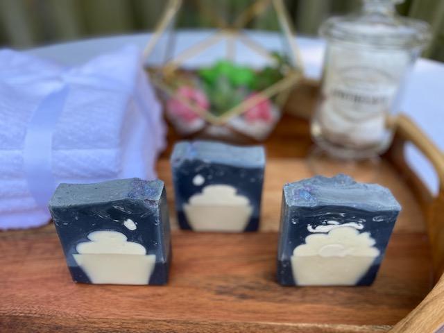 Photo of three activated charcoal soaps on wooden table with a blue and white cupcake design