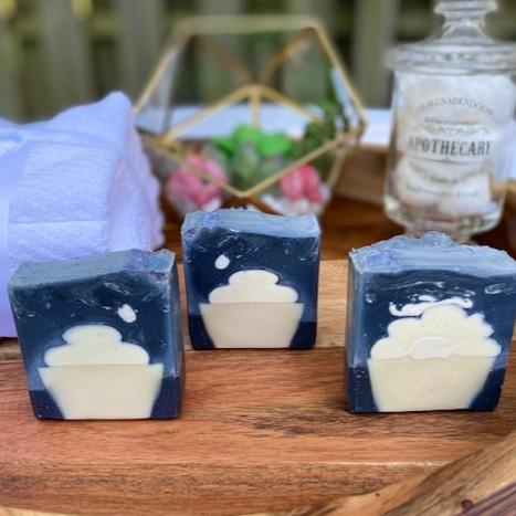 Photo of three activated charcoal soaps on wooden table with a blue and white cupcake design